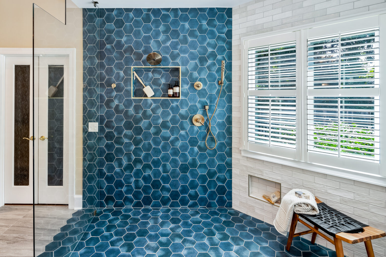 Curbless wet room with deep blue hexagon tile, a rainfall shower head and brass fixtures