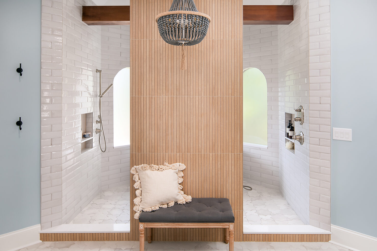 Twin walk-in showers either side of a slatted oak divider with a bench and beaded chandelier