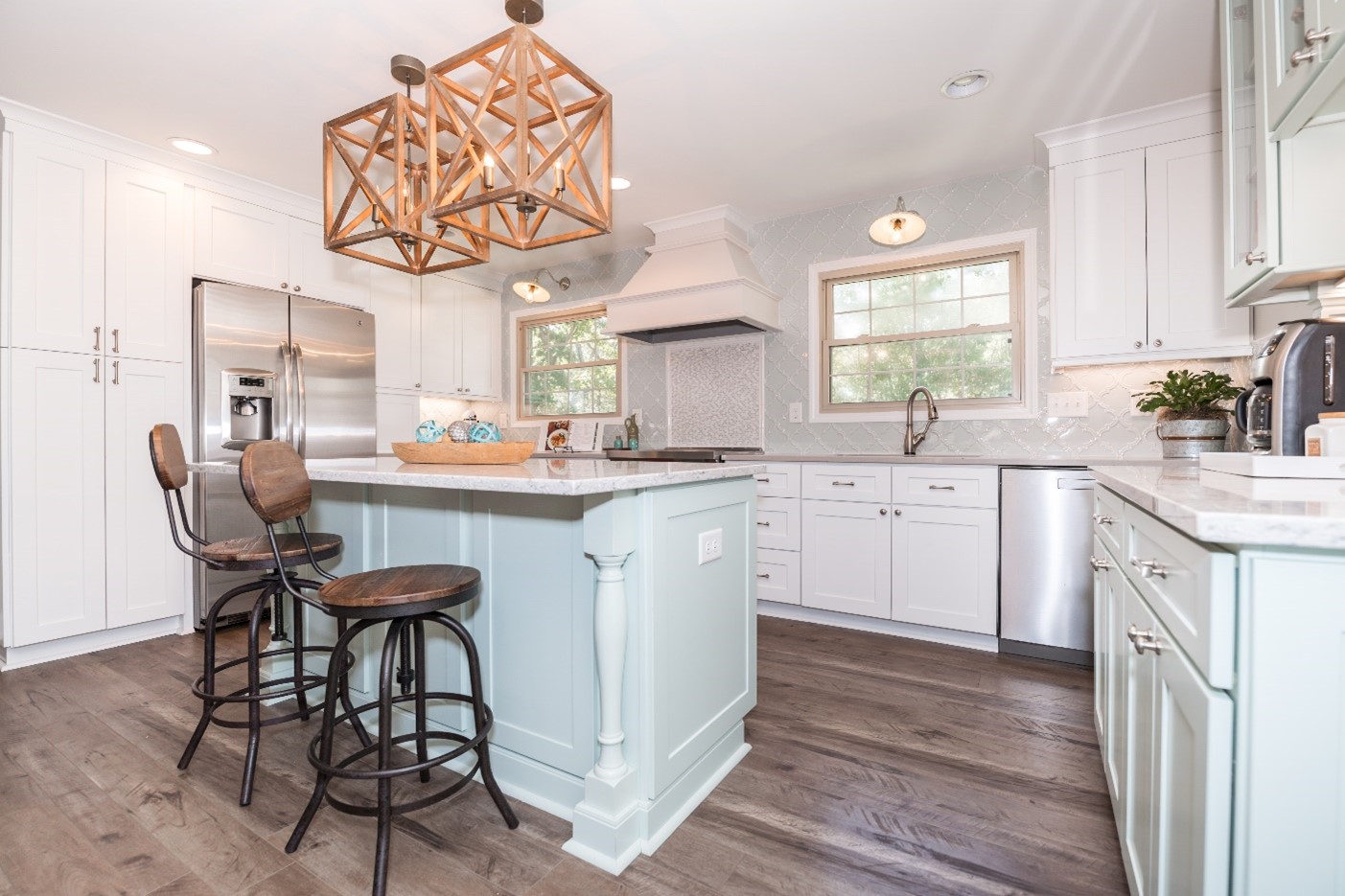 Bright kitchen with a pale blue island, white cabinetry and open sight lines to the next room
