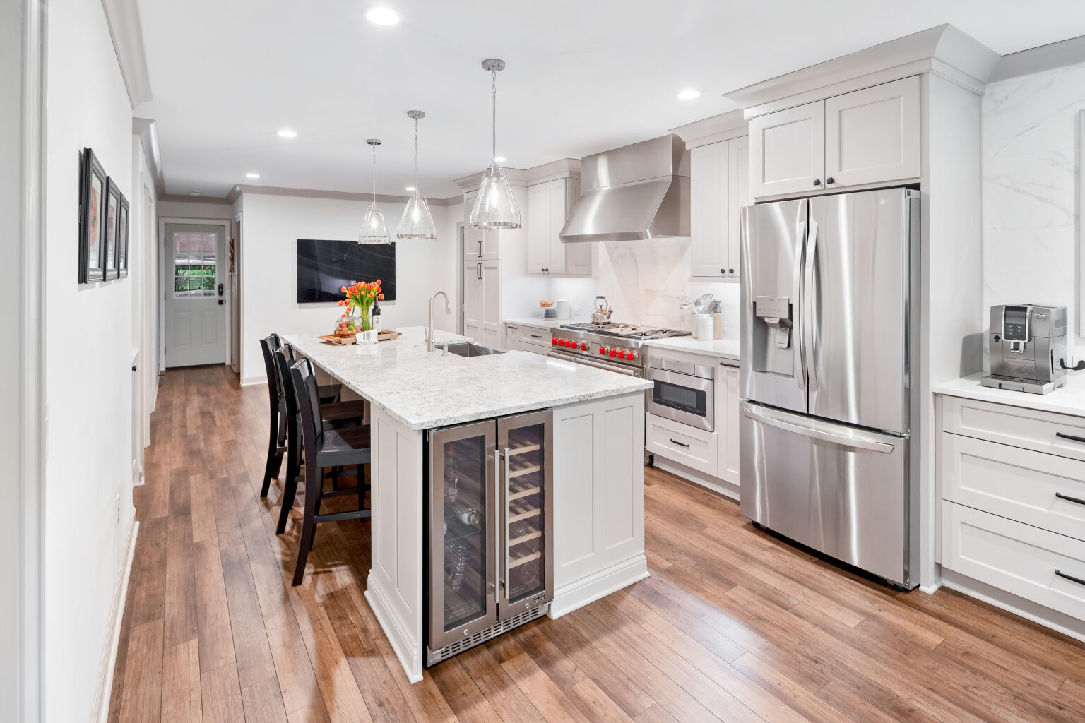 Bright white kitchen with a quartz island, wine fridge and stainless appliances