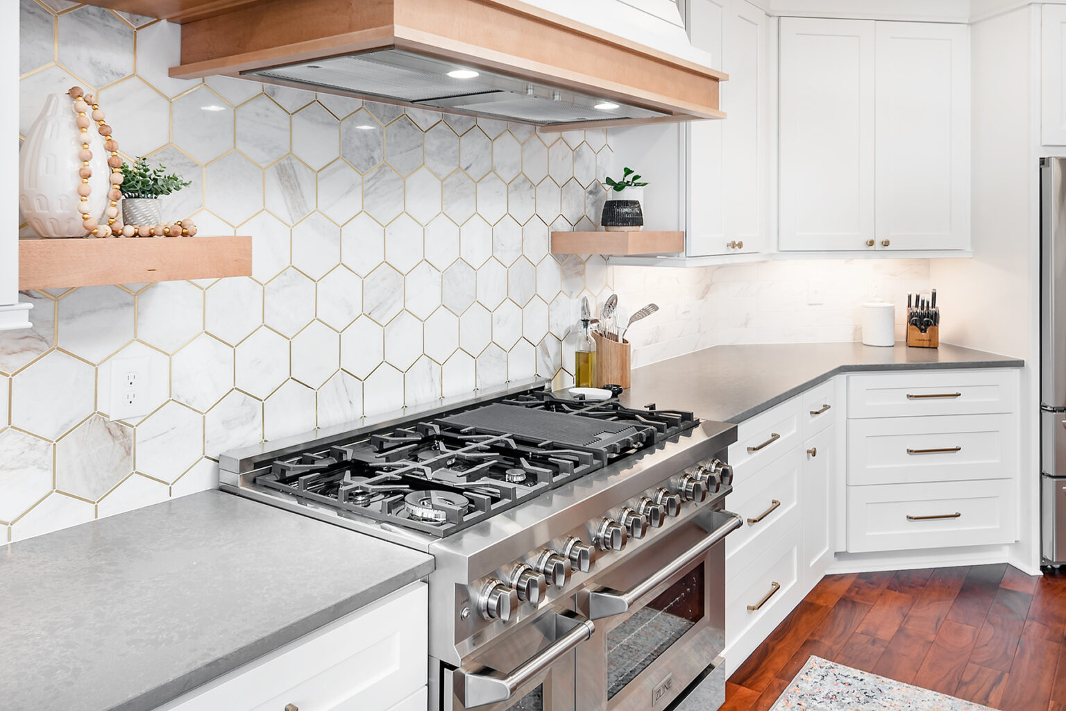 Remodeled kitchen with marble hexagon backsplash, floating shelves and a stainless range