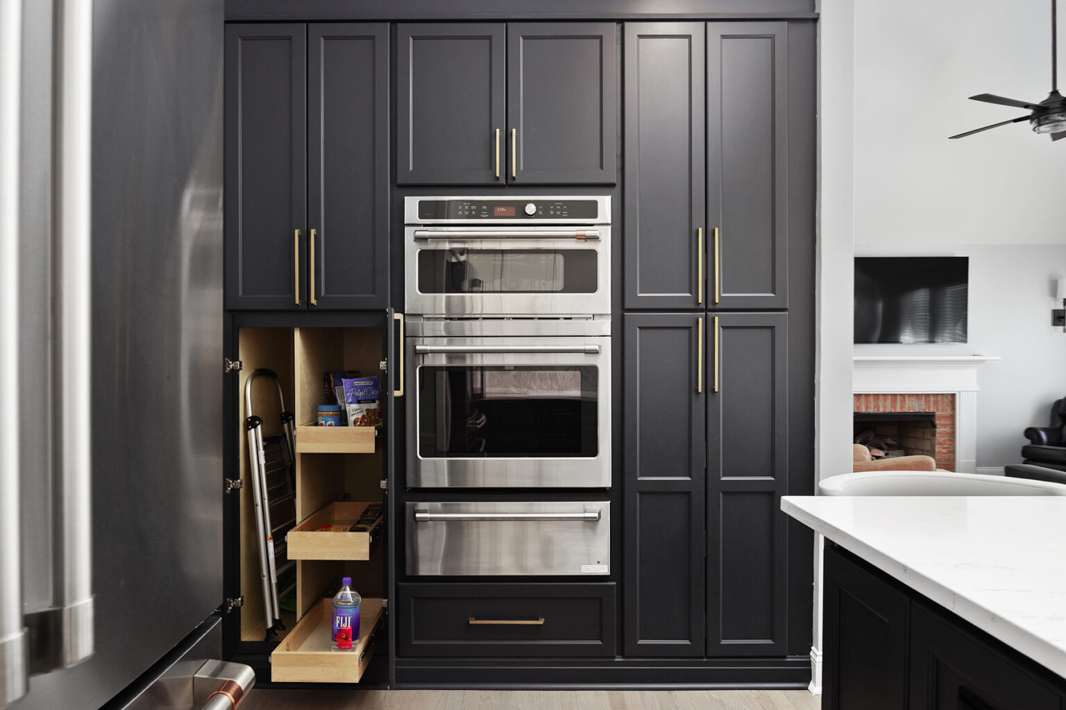 Charcoal kitchen cabinetry with brass hardware and white quartz counters